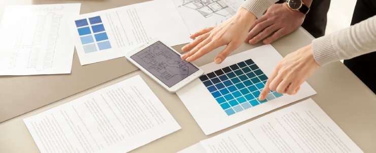 Close up view of Interior designers teamwork with pantone swatch and house building plans on office desk, architects working with blue color palette to choose best paint for home refurbishment