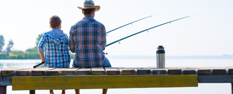 boy and his father fishing together from a pier