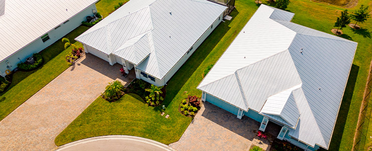 Aerial perspective of a house with a white roof, highlighting choices between metal and clay roofing for new homes.