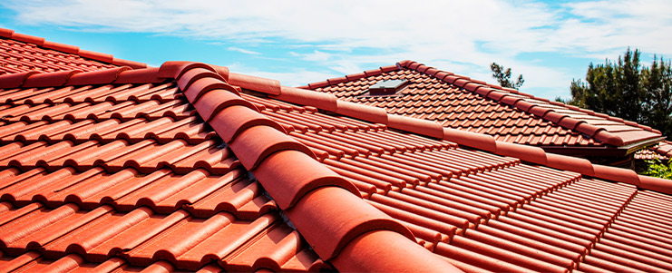 Detailed view of a vibrant red roof under a bright blue sky, highlighting choices in roofing materials for homes.
