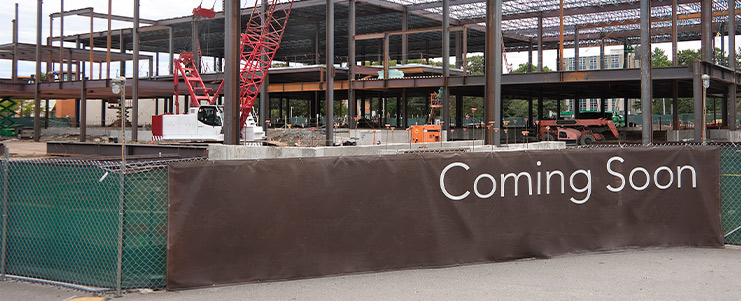 A "Coming Soon" sign stands in front of a building, suggesting that it will be opening or undergoing renovations soon.